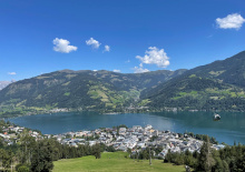 Blick auf Zell am See mit Zeller See, Bergen und der Schmittenhöhe bei schönem Wetter.
