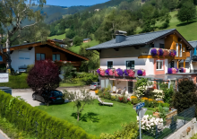 Schwaiger Appartements in Zell am See mit blühendem Garten und Bergblick.