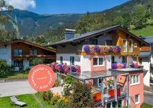 Hausansicht der Schwaiger Appartements im Sommer mit blühenden Balkonen und Bergen in Zell am See